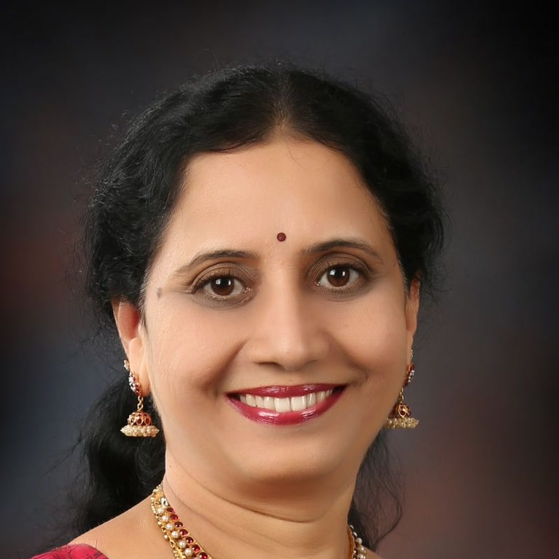 Studio portrait of Dr. P. Lakshmi Satish in a red and gold saree.